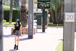 Una joven pasea en Murcia bajo un termómetro que marca 45 grados, en una imagen de archivo.