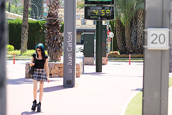 Una joven pasea en Murcia bajo un termómetro que marca 45 grados, en una imagen de archivo.