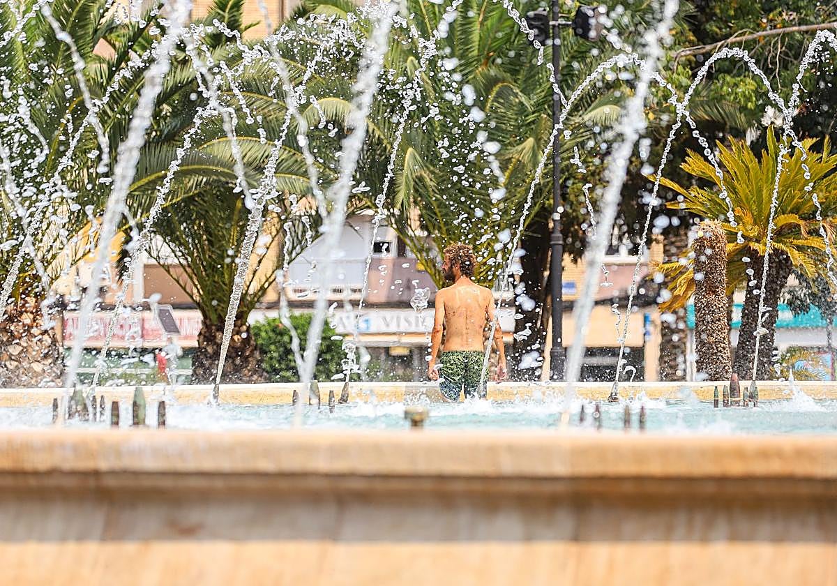 Un hombre se refresca en la fuente de la Plaza Circular de Murcia, este domingo.
