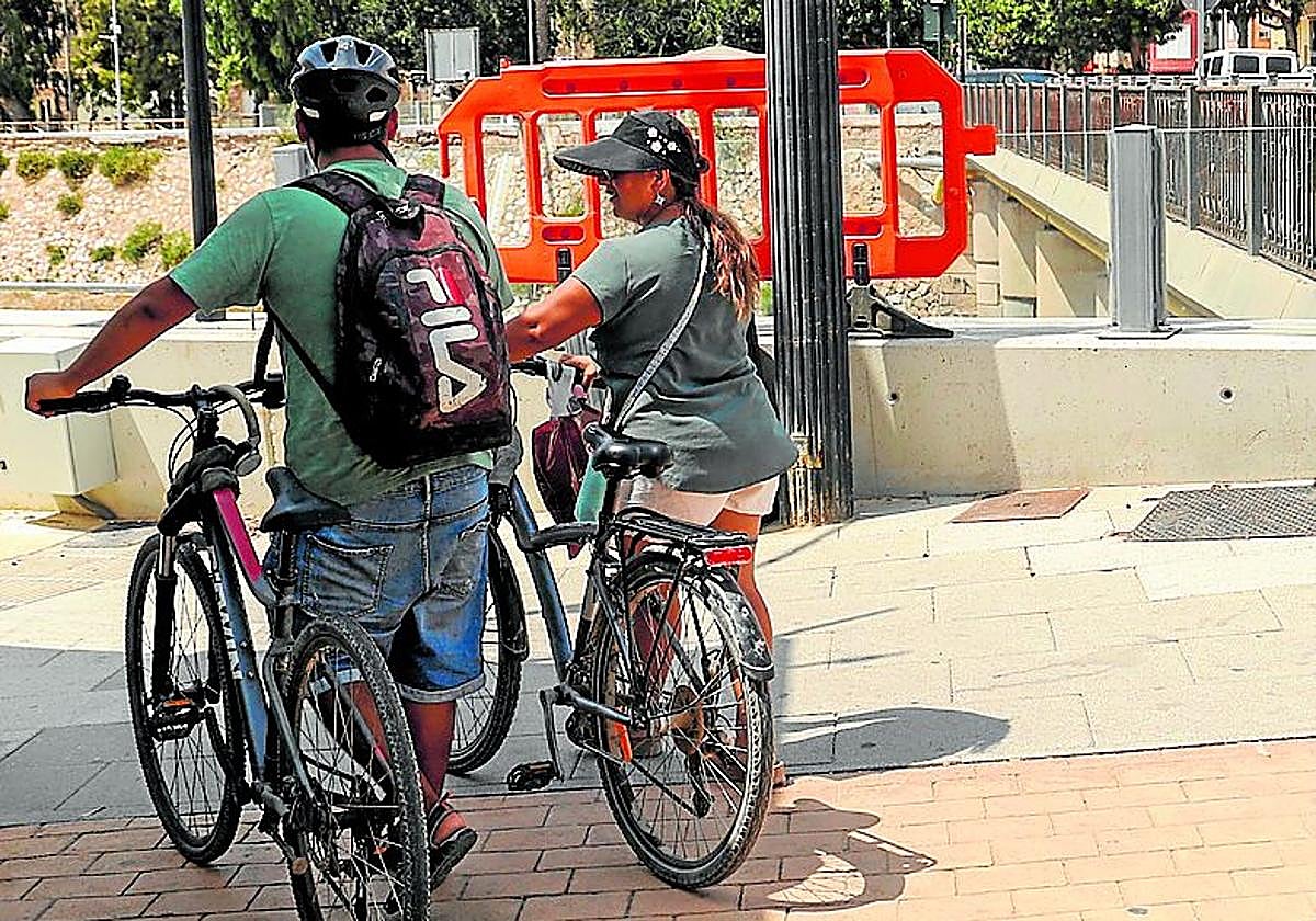 Dos ciclistas pasean junto al puente de Quitapellejos.
