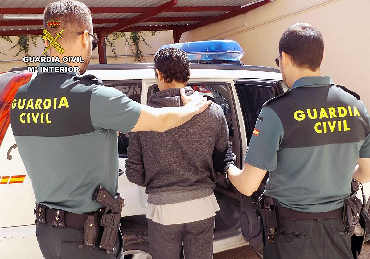 Dos agentes detienen a uno de los sospechosos.