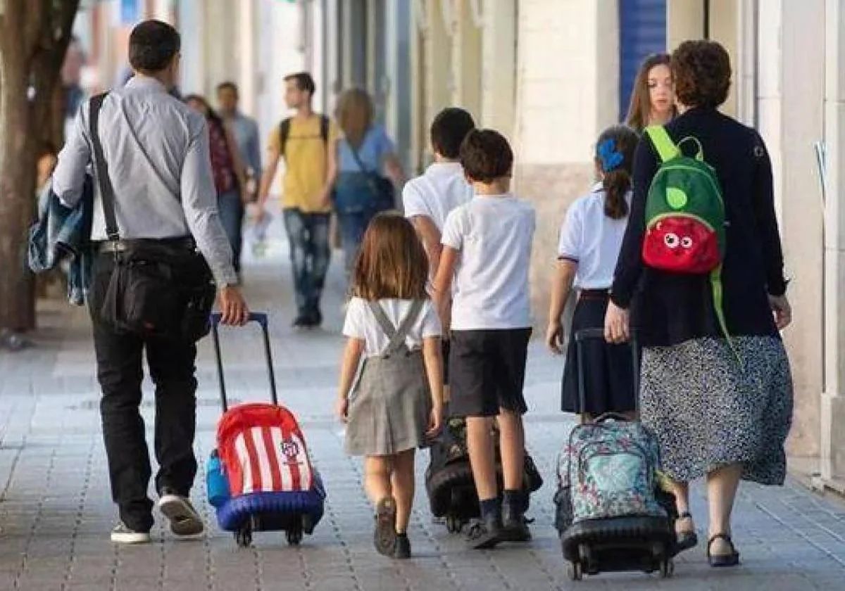 Imagen de archivo de unos padres llevando a sus hijos al colegio.