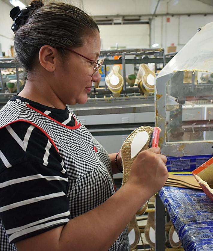 Imagen secundaria 2 - 1. Un trabajador revisa el calzado en los moldes de la fábrica. 2. Una operaria adpta la suela de yute. 