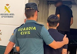 Un guardia civil conduce al furgón a uno de los detenidos.
