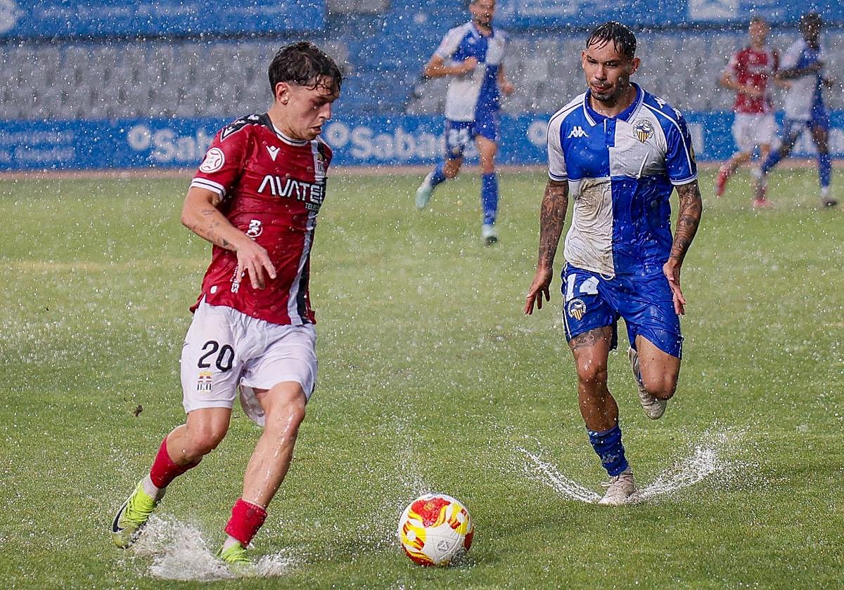 Diego Gómez conduce el balón en el césped encharcado de la Nova Creu Alta.
