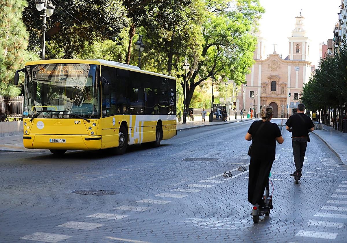 Un autobús circula por la Alameda de Colón, en Murcia, mientras dos usuarios de patinete usan el carril-bici.