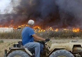 Un agricultor observando el fuego desde su tractor