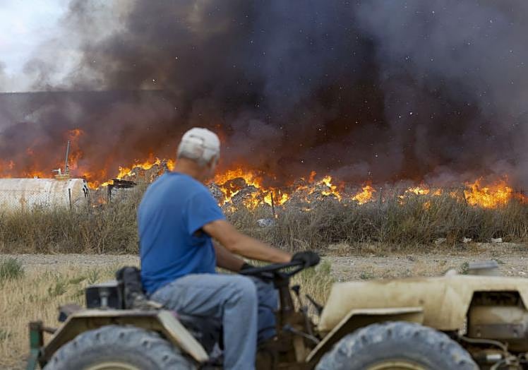 Un agricultor observando el fuego desde su tractor.