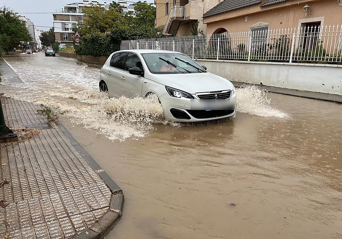 Un vehículo atraviesa la carretera de Churra, en Murcia, anegada de lluvia.