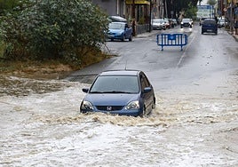 Un coche atraviesa el agua embolsada en la rambla del Secano de Torreagüera, en Murcia.