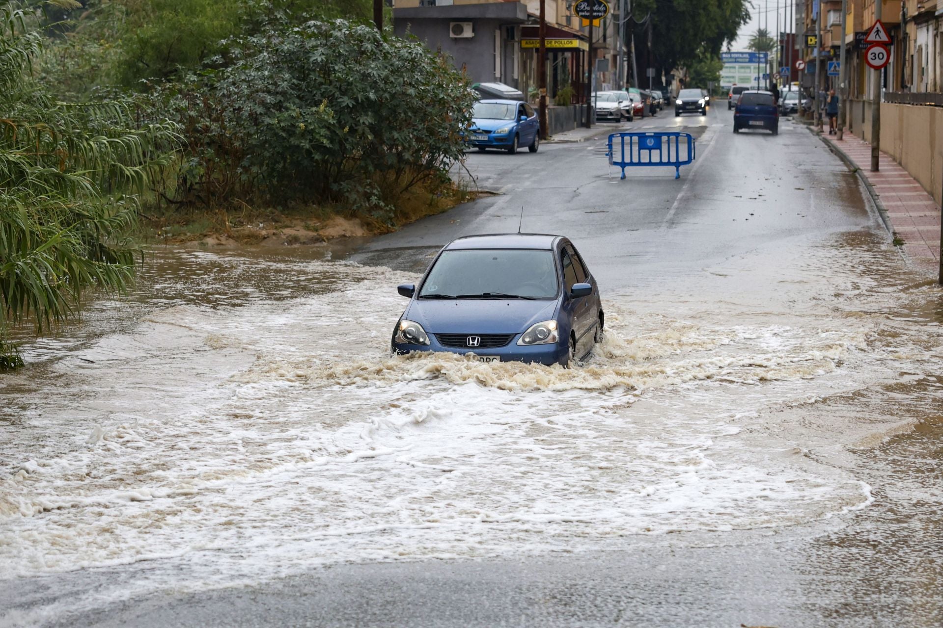 Un coche atraviesa el agua embolsada en la rambla del Secano de Torreagüera, en Murcia.