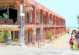 Grupos de bañistas pasan junto al edificio que será demolido, en la zona norte de La Manga.