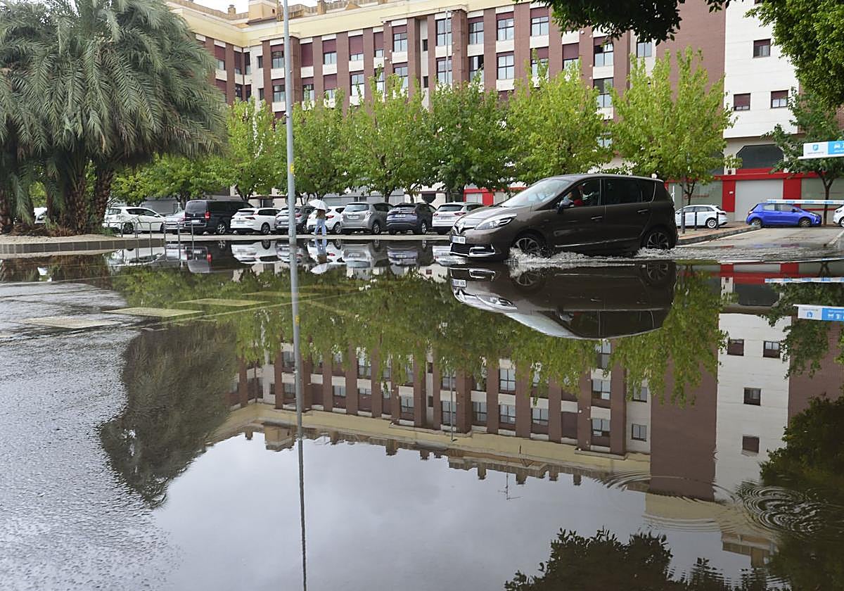 Un coche circula por un parking de Murcia anegado por las lluvias de la semana pasada.