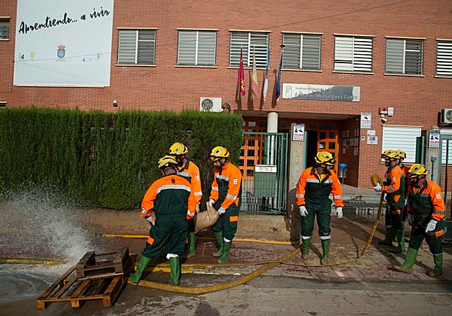 Brigadas de la Comunidad achican agua del instituto Menárguez Costa de Los Alcázares, este domingo.