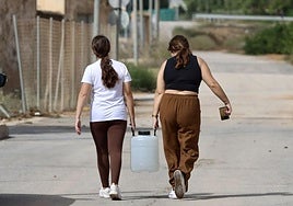 Dos jóvenes transportan una garrafa de agua tras el corte del suministro, este domingo.