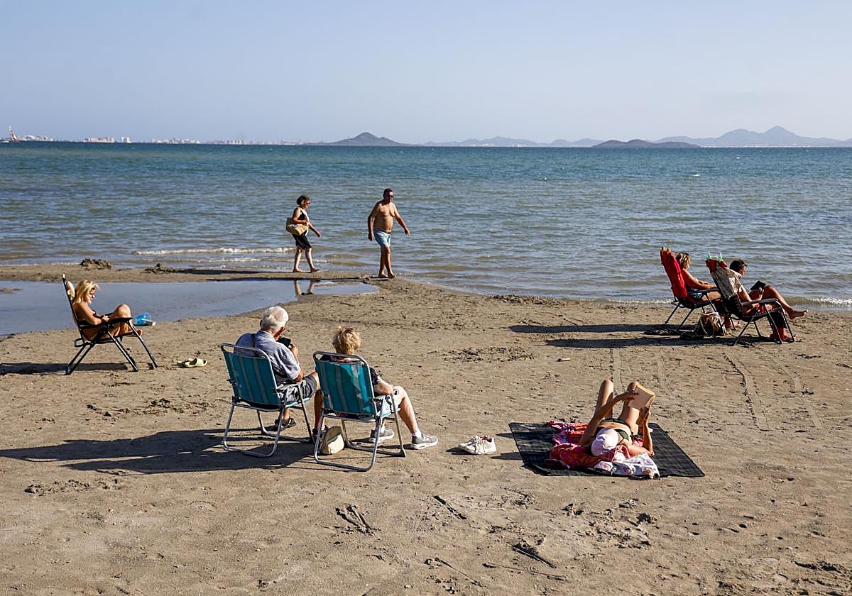 Ocho personas, ayer por la mañana, en la playa del Mar Menor, donde el agua tenía un aspecto marrón por los arrastres de la dana.