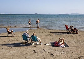 Ocho personas, ayer por la mañana, en la playa del Mar Menor, donde el agua tenía un aspecto marrón por los arrastres de la dana.