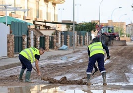Dos operarios retiran barro en San Javier tras el paso de la dana 'Alice'.