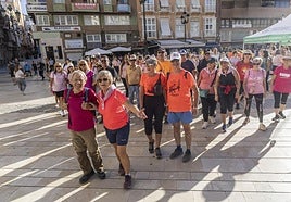 Los participantes en la marcha senderista por el cáncer de mama parten del stand.