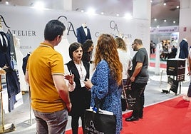 Una pareja charla con una expositora de una marca de moda en Boda&Celebraciones.