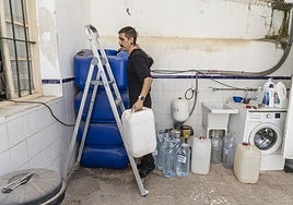 El peluquero Imanol Oliver llena de agua embotellada el depósito de su local en Los Alcázares, en una imagen de la semana pasada.