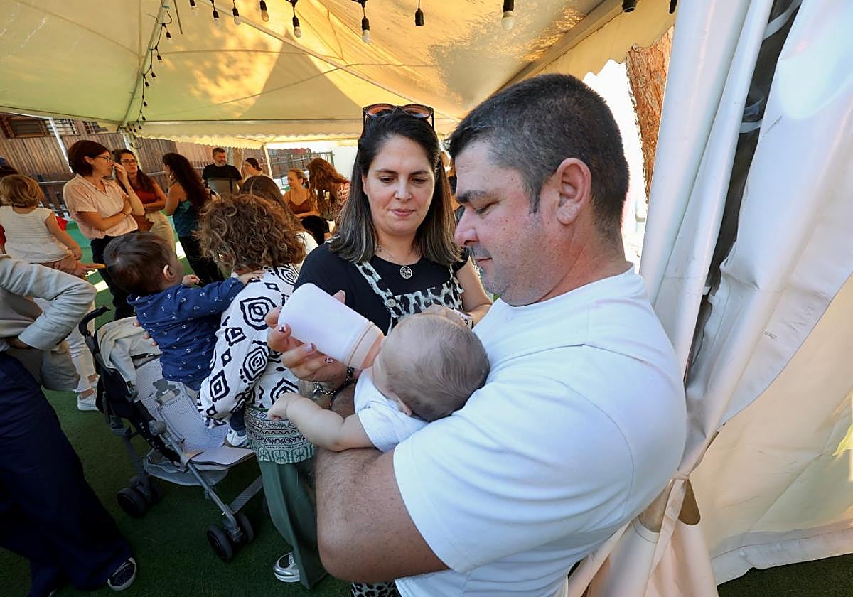 Una pareja da un biberón a uno de los 640 menores tutelados por la Comunidad que viven actualmente con una familia de acogida.