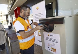 Un empleado de Repsol deposita una botella con aceite usado en el nuevo punto de recogida habilitado en una gasolinera de Cartagena.
