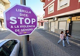 Dos mujeres pasan junto a una señal contra la violencia de género en una calle de Librilla, este lunes.