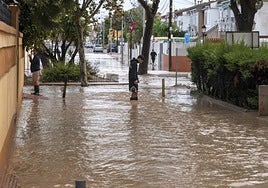 Dos vecinos cruzan una calle de Los Alcázares con botas de agua tras las últimas inundaciones.