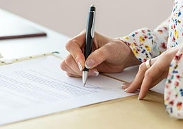 Imagen de archivo de una persona firmando un documento.
