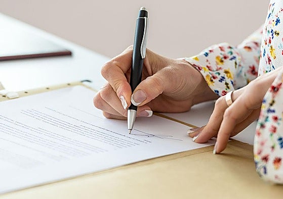 Imagen de archivo de una persona firmando un documento.