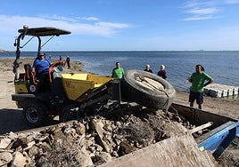 Un operario retira un neumático encontrado en el entorno de la rambla del Albujón, este sábado, durante la jornada de limpieza convocada por Hippocampus.