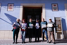 La alcaldesa de Fortuna (3i), Catalina Herrero, junto a vecinos del municipio, con imágenes históricas del repartido Gordo de la Lotería de Navidad que regó de millones de pesetas la localidad.