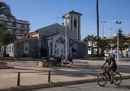 Un vecino pasea con su bici frente a la iglesia de Los Urrutias, ayer.