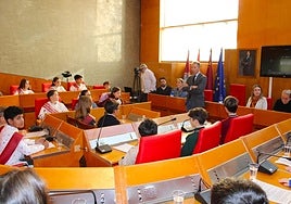 El alcalde da instrucciones a los niños, sentados en los asientos de los concejales, antes del inicio del Pleno Infantil.