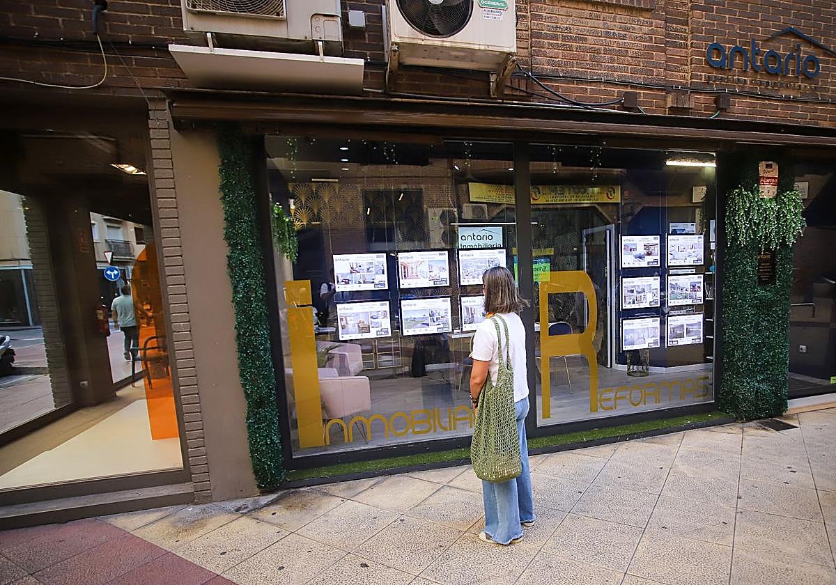 Una mujer revisa los anuncios de viviendas en una inmobiliaria.