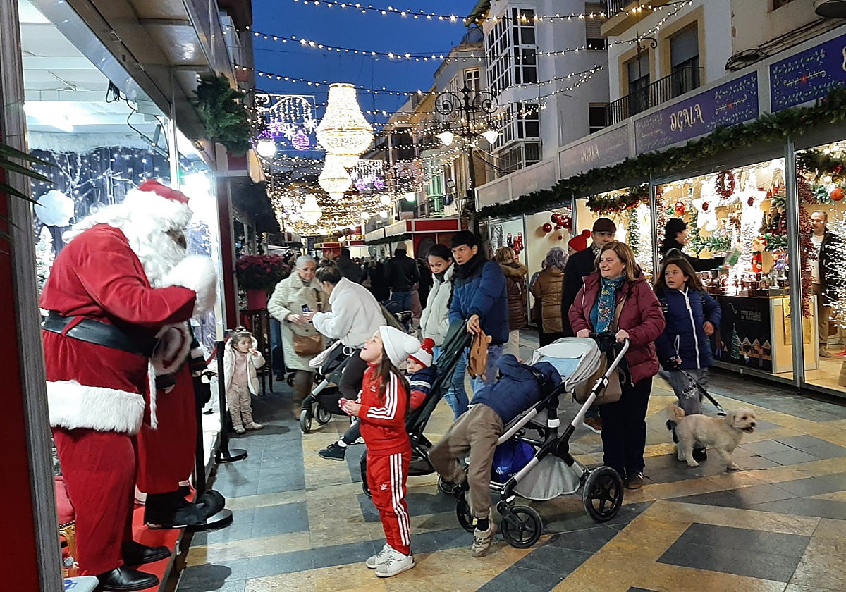Una niña saluda a Papá Noel en el mercadillo navideño.