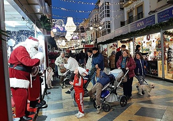 Una niña saluda a Papá Noel en el mercadillo navideño.
