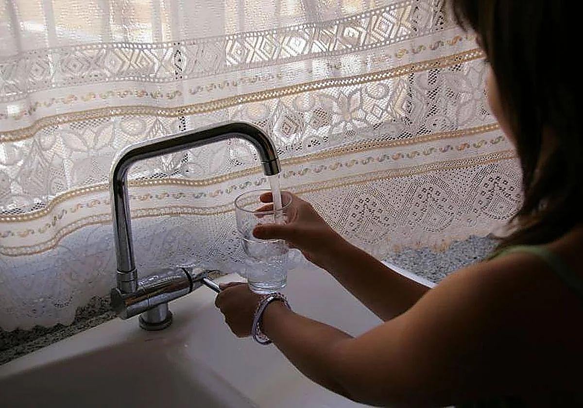 Una mujer echa agua en un vaso.