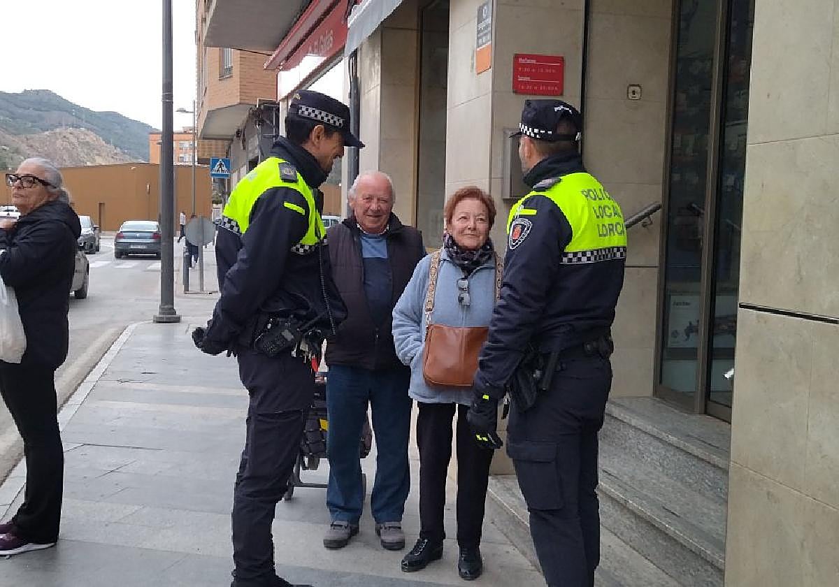 Los agentes conversan en la calle Mayor con una vecina del barrio de San Cristóbal que lleva el bolso colgado al cuello para evitar que se lo roben.