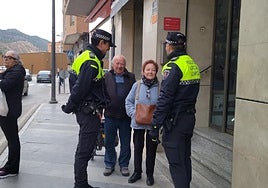Los agentes conversan en la calle Mayor con una vecina del barrio de San Cristóbal que lleva el bolso colgado al cuello para evitar que se lo roben.