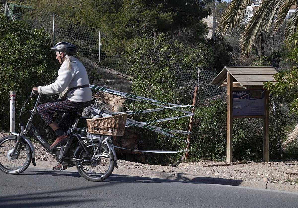 Una ciclista pasa frente al acceso de la Cueva del Agua, precintada tras la muerte de la buceadora.