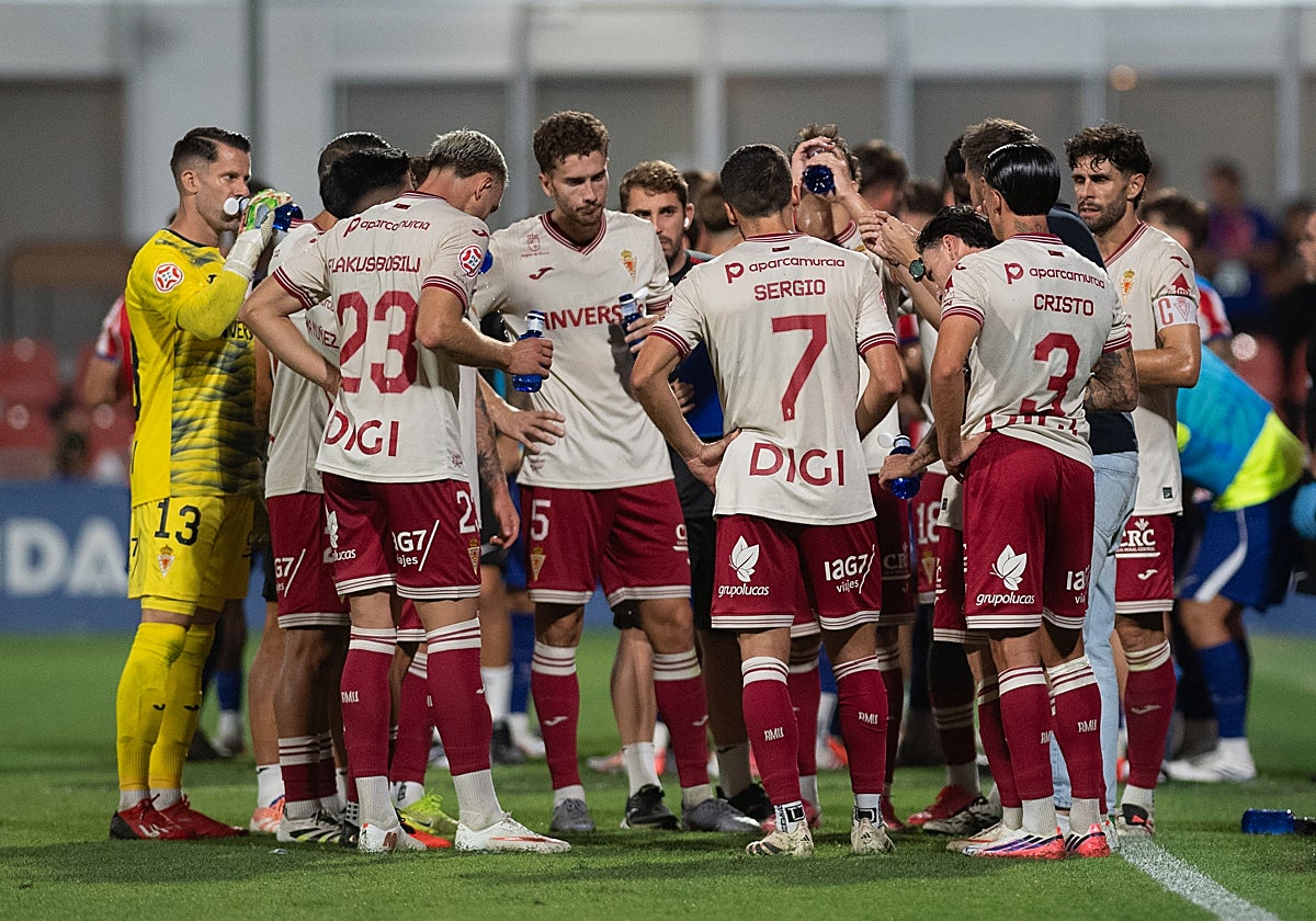 Los jugadores del Real Murcia atienden a Guilló durante la pausa por hidratación del segundo periodo.