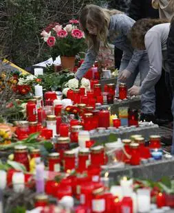 La entrada del colegio ha amanecido sembrada de velas, flores, carteles y muñecos de peluche para recordar a las víctimas. / Afp