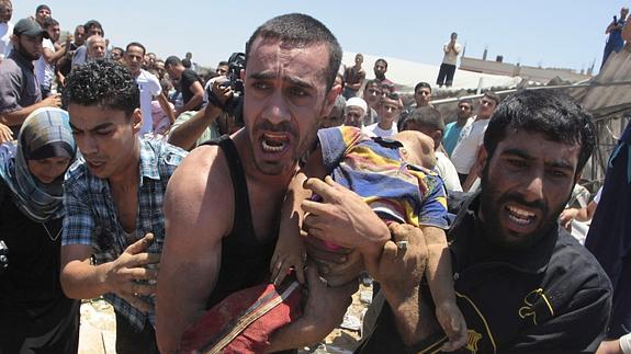 Un hombre traslada el cadáver de un niño en Gaza./ 