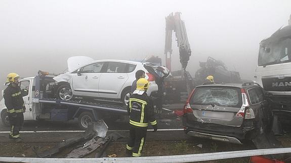 Dos bomberos ante dos de los camiones implicados en un accidente múltiple en Lugo. Efe