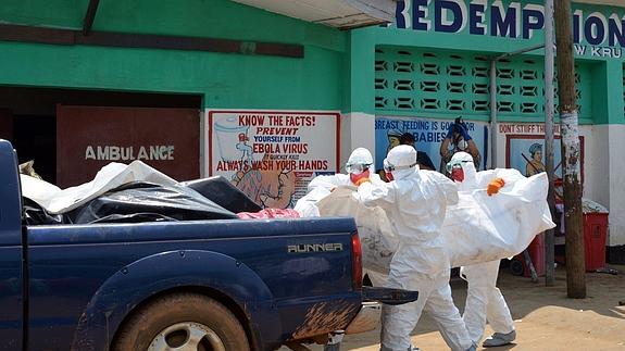 Miembros de la Cruz Roja retiran varios cadáveres de personas afectadas por el virus. 