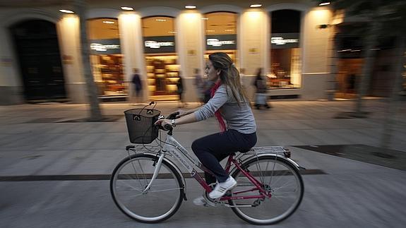 Una mujer pasea en bicicleta por la Calle Serrano de Madrid. 