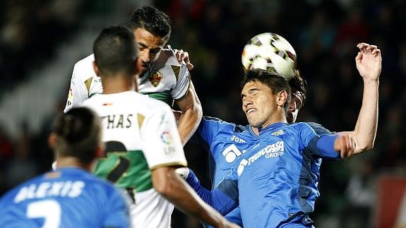 El defensa uruguayo del Getafe, Emiliano Daniel Velázquez (d), despeja un balón ante los atacantes del Elche.