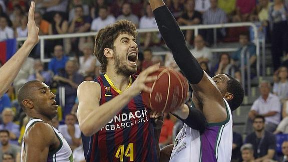 Tomic (c) protege al balón entre dos jugadores de Unicaja. 